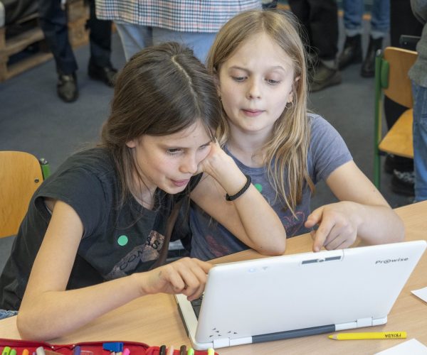 Zwei Mädchen sitzen konzentriert an einem Laptop
