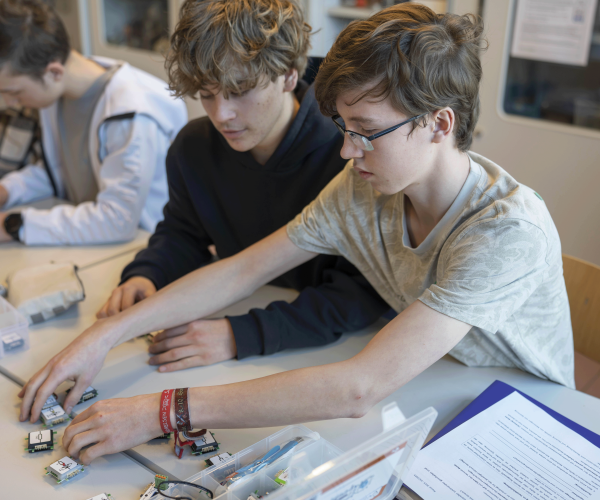 Zwei Schüler stecken in einem Klassenraum Elektrobauteile zusammen